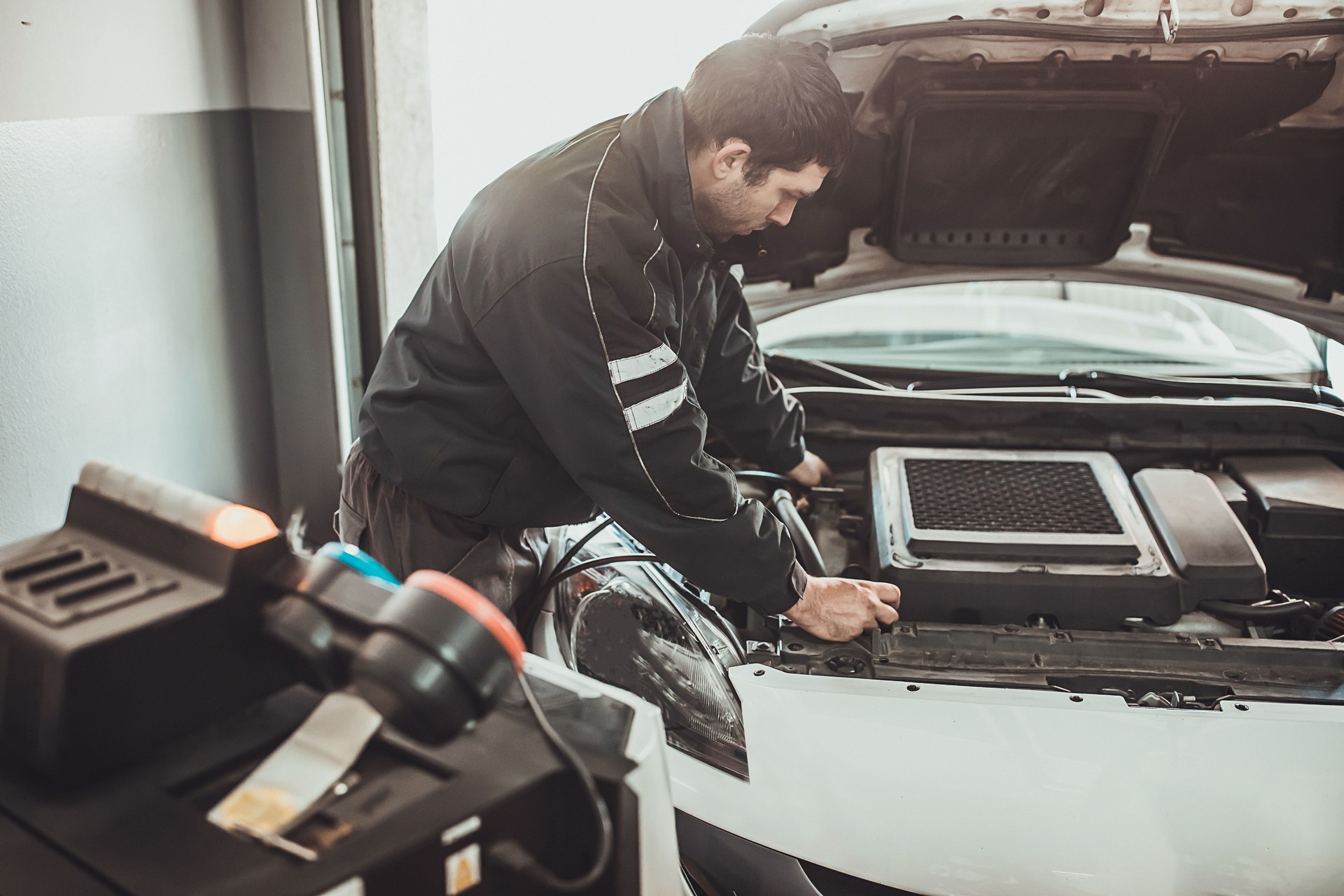 Mechanic recharging car air-condition in auto repair shop