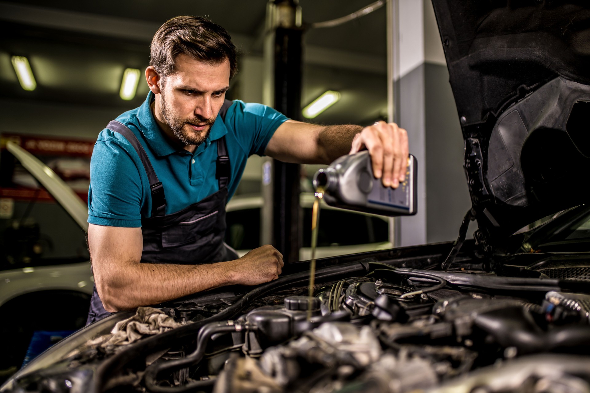 Mechanic changing oil on the vehicle at car workshop.