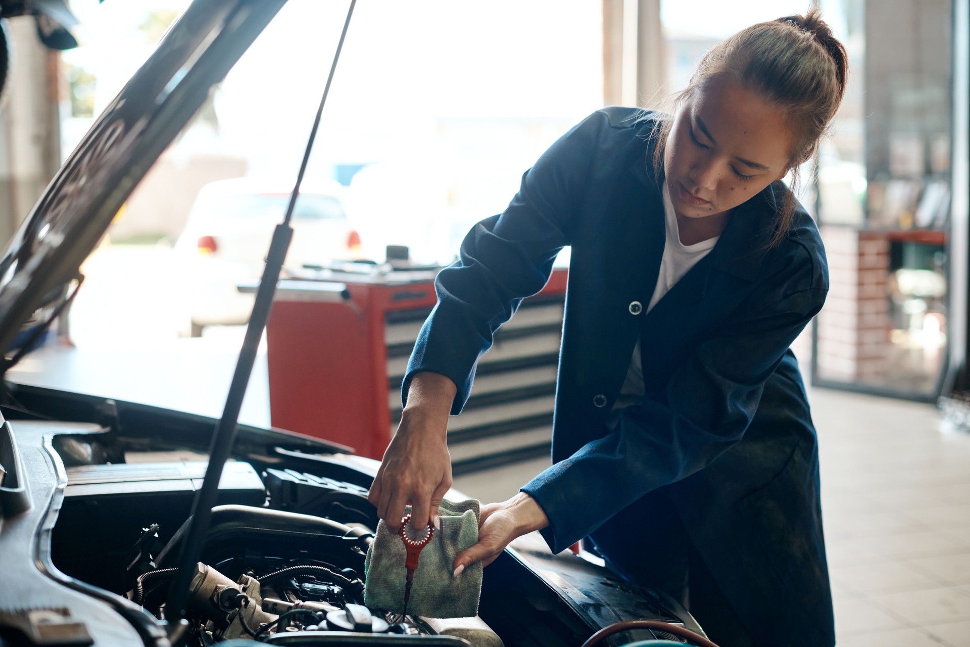 Shot of a mechanic pulling out the dipstick to check a car's oil level